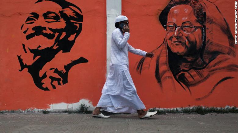 A man walks past a wall with images of Bangladeshi founding father Sheikh Mujibur Rahman and Prime Minister Sheikh Hasina Wazed in Dhaka, Bangladesh. 