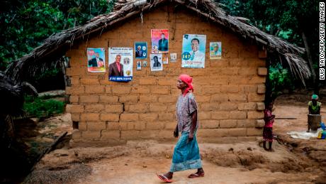 A woman walks in front of electoral posters in the remote village of Bonde, Kongo Central province, on December 26.