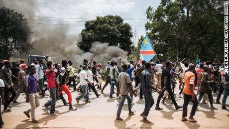 Protesters march in front of a police platoon near the electoral commission in Beni on December 27.