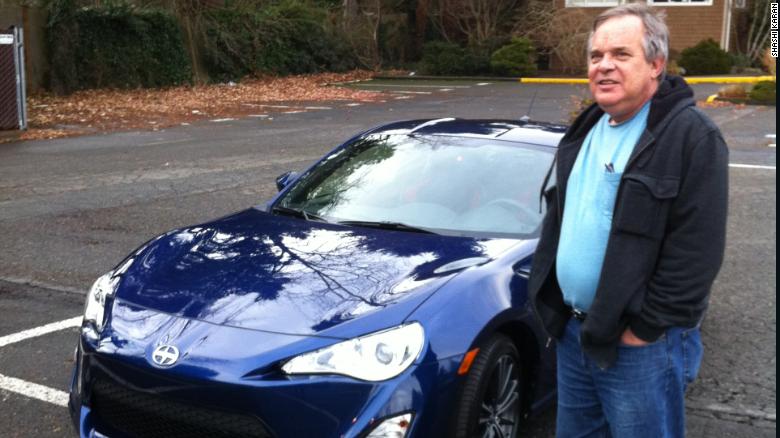 Alan Naiman poses next to one of his few splurges -- a Scion sports car. The thrifty social worker left more than $11 million to charities when he died in January.
