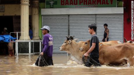 This photo taken on December 30, 2018 shows people walking through a flooded street in the town of Baao in Camarines Sur province.