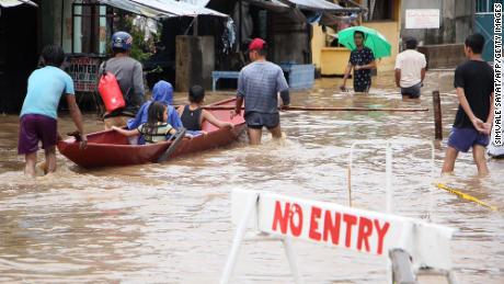 People wade through flooded streets in the town of Baao in Camarines Sur province on December 30.