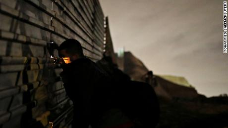 A man looks through the fence as he and others prepare to cross it illegally on Monday.