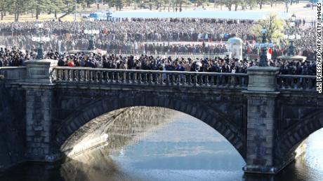 People walk along on a bridge leading to the Imperial Palace to attend Akihito's last New Year greeting ceremony in Tokyo.