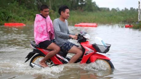 Thai men ride a motorcycle Friday through floodwaters from Tropical Storm Pabuk in the Pak Panang district of Nakhon Si Thammarat province.