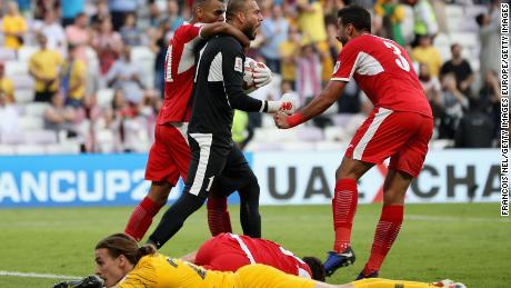 Socceroo Jackson Irvine looks dejected as Jordan players celebrate after winning their AFC Asian Cup Group B opening match.