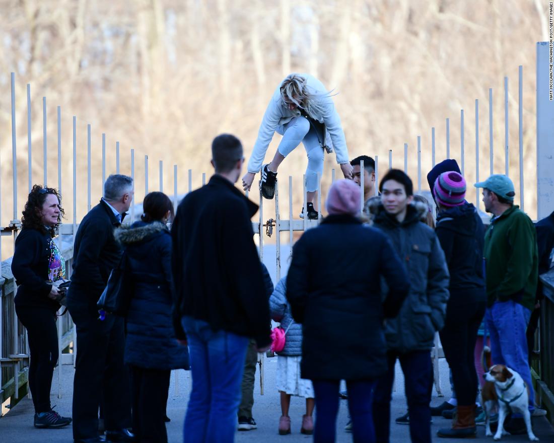 A pedestrian in Arlington, Virginia, climbs over a fence leading to Theodore Roosevelt Island, which was closed because of the government shutdown on Sunday, January 6.