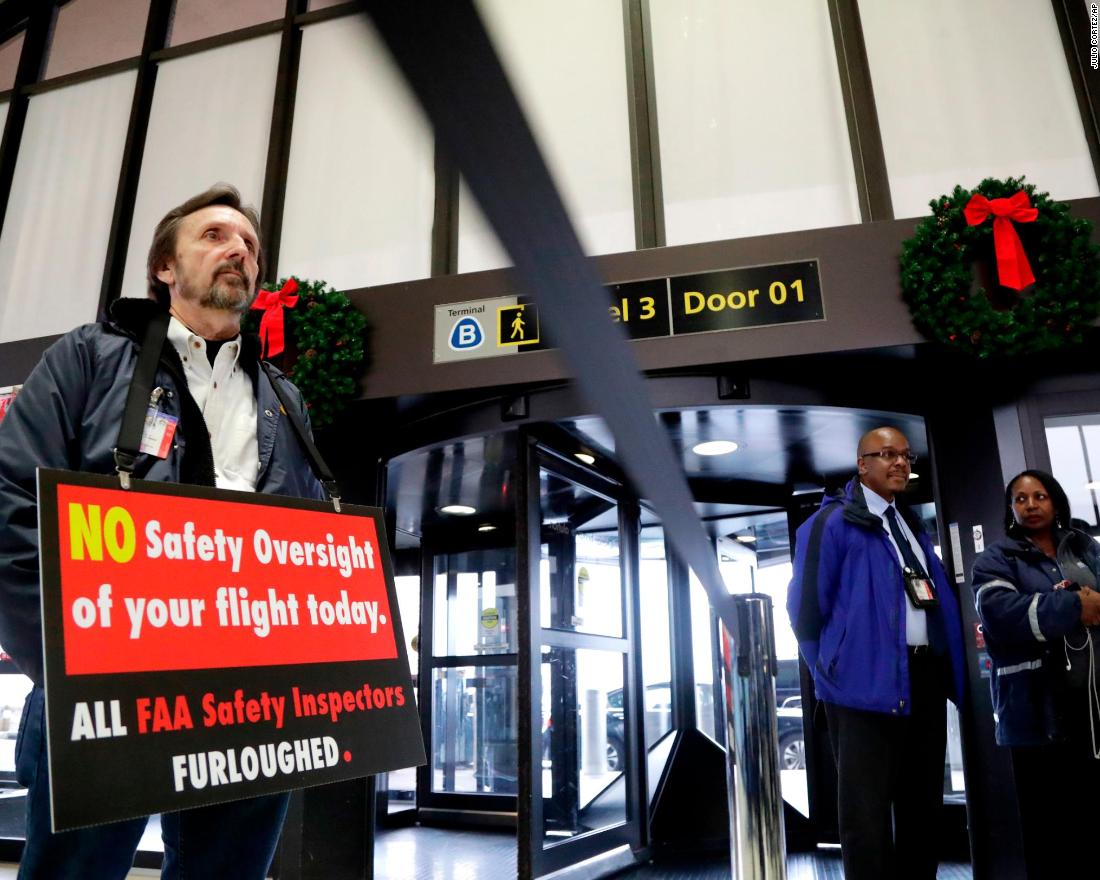 Federal Aviation Administration employee Michael Jessie, who was working without pay as an aviation safety inspector, holds a sign Tuesday, January 8, while attending a news conference at Newark Liberty International Airport in New Jersey. 