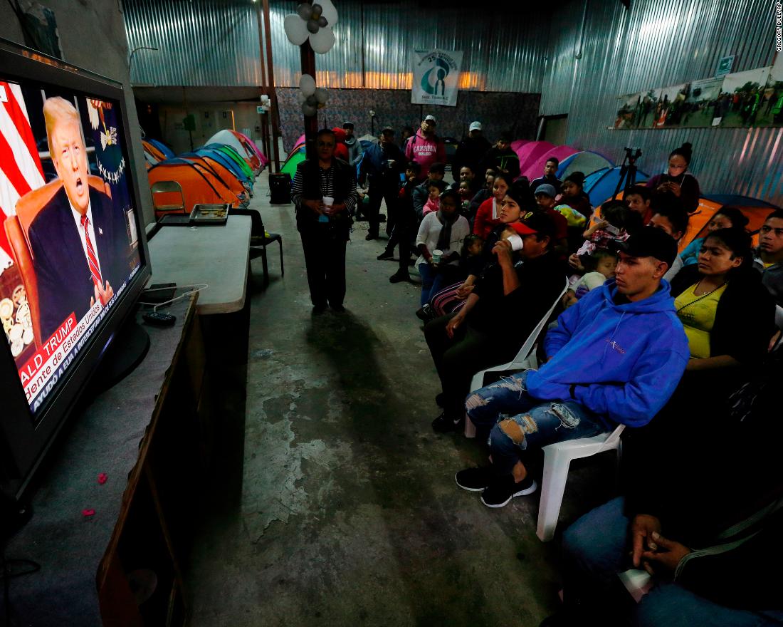 Migrants from Mexico and Central America watch Trump&#39;s speech from a shelter in Tijuana, Mexico, on January 8.