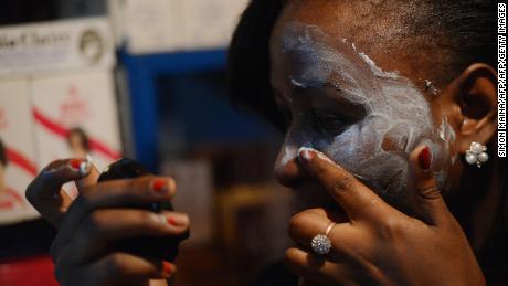 A Kenyan beautician illustrates how to apply skin-lightening cream.