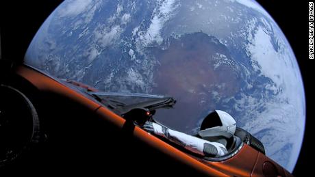 A dummy in a spacesuit is seen behind the wheel of Elon Musk's red Tesla sports car as it floats in space.