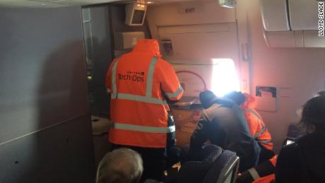 Passenger Steven Lau posted this photo of United workers trying to fix an emergency exit door.