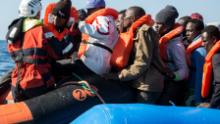 A group of 47 migrants is helped by a Sea Watch 3 crew member (left) during a rescue operation off Libya in January 2019. 