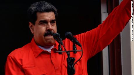 Venezuelan President Nicolas Maduro speaks to a crowd of supporters at the Miraflores Palace flanked by his wife Cilia Flores (2-L) and Vice-President Delcy Rodriguez (R), as he holds up the document with which his government broke off diplomatic ties with the United States.