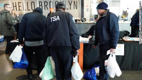 Furloughed TSA employees and others leave the Barclays Center in New York with bags of donated food.