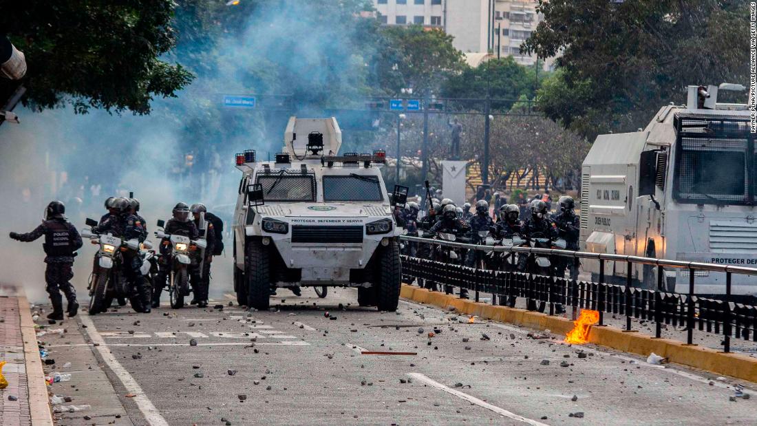 Security forces stand in a street full of stones after clashing with demonstrators in Caracas.