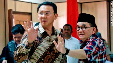 Jakarta Governor Basuki Tjahaja Purnama, popularly known as "Ahok" (left) and his campaign spokesman Ruhut Sitompul (right) wave to photographers after his trial for blasphemy at the North Jakarta District Court in Jakarta on December 13, 2016.