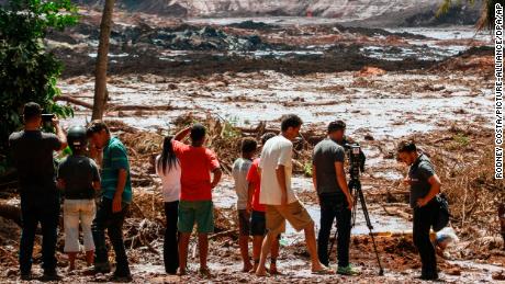 People observe the mud masses Friday after the break of the dam at the Feijao mine. 