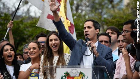 The head of Venezuela's National Assembly and the country's self-proclaimed "acting president" Juan Guaido (R) speaks next to his wife Fabiana Rosales (C) and activist Lilian Tintori (L), wife of Venezuelan opposition leader Leopoldo Lopez, to a crowd of opposition supporters in Caracas, on January 26, 2019. 