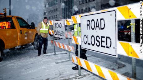 City workers put up a road closed sign on the Michigan Street hill in Grand Rapids, Mich., Monday, Jan. 28, 2019. Snow made travel dangerous is many areas of the state. Heavy snow and gusting winds created blizzard-like conditions Monday across parts of the Midwest, prompting officials to close hundreds of schools, courthouses and businesses, and ground air travel. (Neil Blake/The Grand Rapids Press via AP)