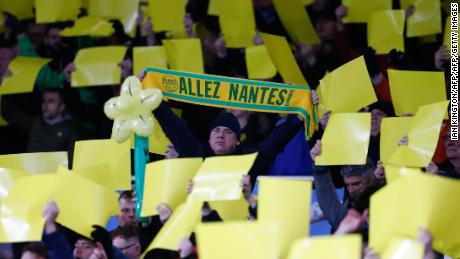 Fans hold up yellow banners and a Nantes scarf.