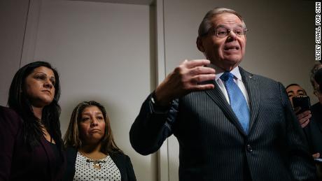 Sandra Diaz, left, and Victorina Morales stand by as Sen. Bob Menendez delivers remarks to reporters.