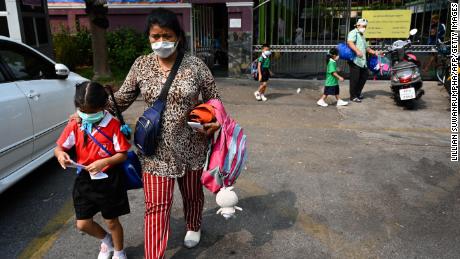 A woman picks up a child from school early due to toxic levels of air pollution in Bangkok on Wednesday. 