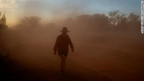 An Australian farmer walks through a cloud of dust on her property on January 16.