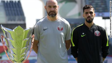 Qatar&#39;s head coach Felix Sanchez with player Hasan Al Haydos pose next to the Asian Cup trophy ahead of the final.