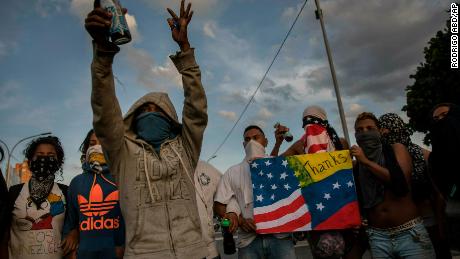 Anti-government protesters prepare to sing Venezuela's national anthem while blocking a highway in Caracas on February 2, 2019.