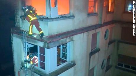 Firemen scale the top floors of the burning building.