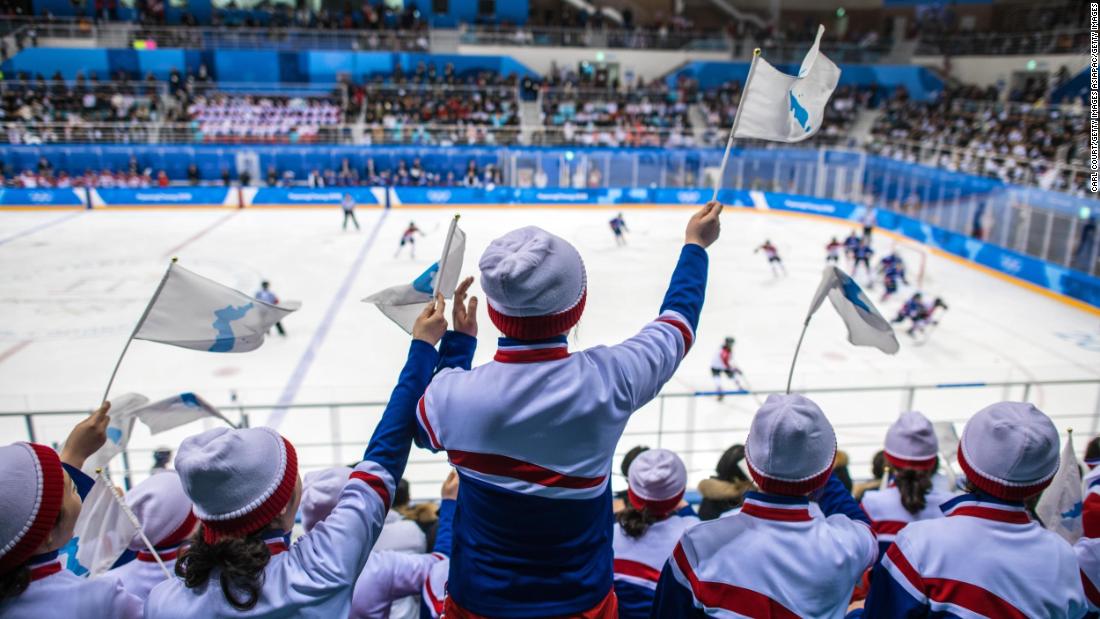 North Korean cheerleaders wave unified Korean flags.