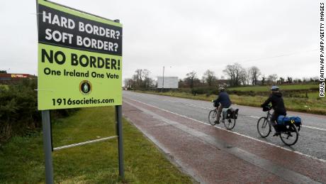 Cyclists pass a sign calling for no border to be imposed between Ireland and Northern Ireland outside Newry, Northern Ireland, on November 14, 2018 near the Irish border. - British Prime Minister Theresa May defended her anguished divorce deal with the European Union before rowdy lawmakers on Wednesday before  trying to win the backing of her splintered cabinet with the so-called &quot;Irish backstop&quot; arrangement to guard against the imposition of a hard border between Ireland and Northern Ireland one of the contentious issues, according to reports. (Photo by Paul FAITH / AFP)        (Photo credit should read PAUL FAITH/AFP/Getty Images)