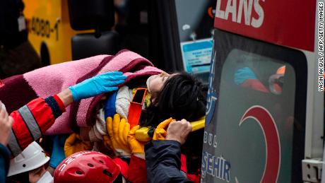 A child is carried Thursday from the site of the building collapse after being rescued from the rubble.