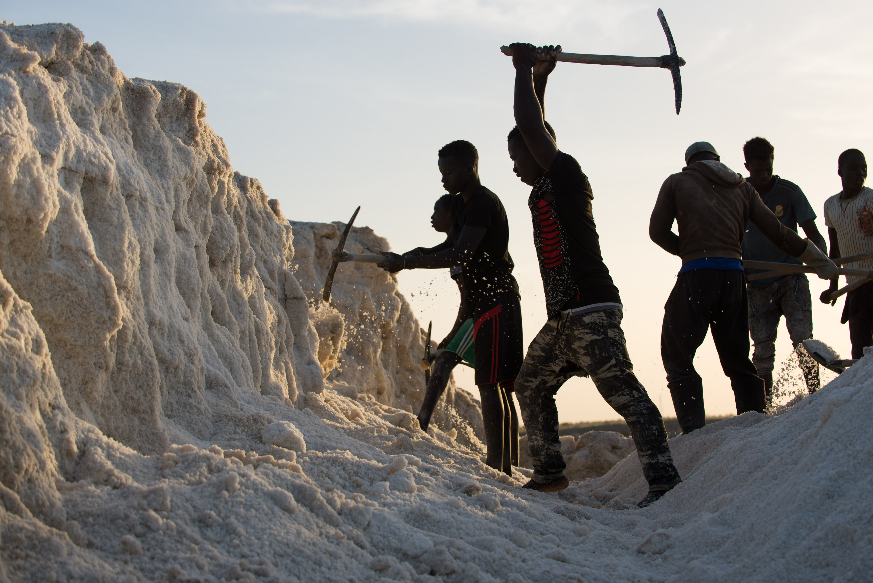 Young men chip away at a hardened mount of salt on Diouf&#39;s land in Fatick.