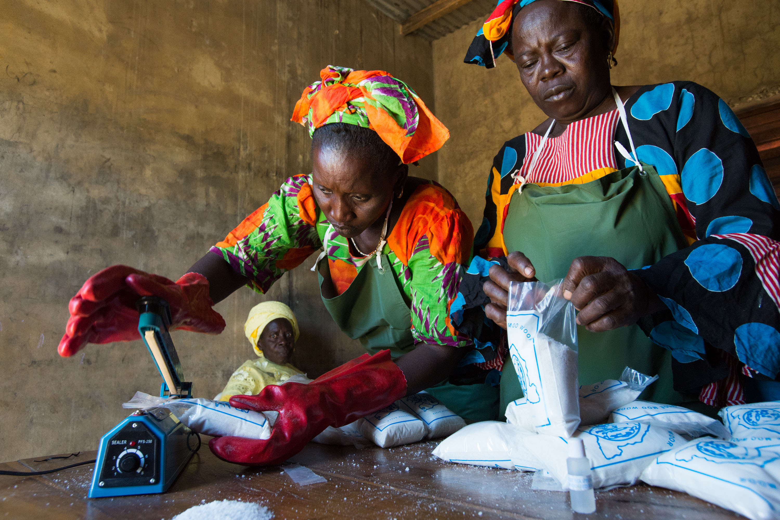 Ndeye Faye, top left, and Seynabou Diouf, right, test salt for iodine content before sealing it in plastic bags, while Fatou Sarr, bottom left, looks on. Marie Diouf employs the women in her micro-business producing and packaging iodized salt.