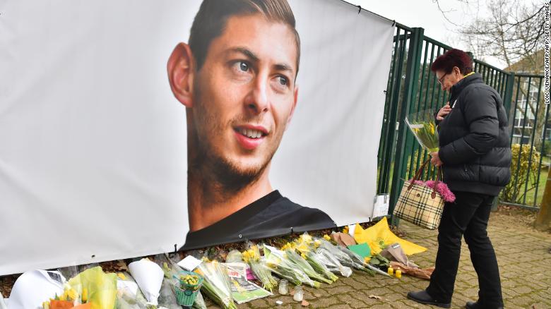 A woman lays flowers beside a portrait of Argentinian forward Emiliano Sala.