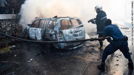 A firefighter extinguishes a car fire at the offices of Television Nationale d&#39;Haiti during protests in Port-au-Prince on Wednesday. 