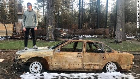 Nate Bailey stands on top of his burned out car in Paradise, California. 