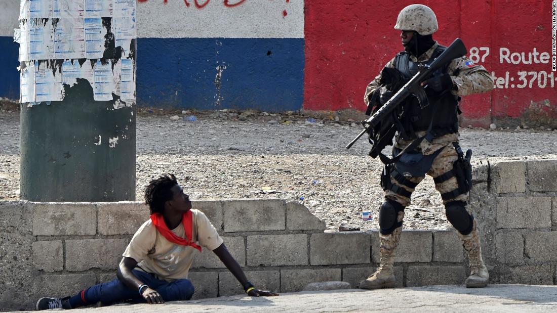 A police officer questions a man near the airport in Port-au-Prince on Friday, February 15.