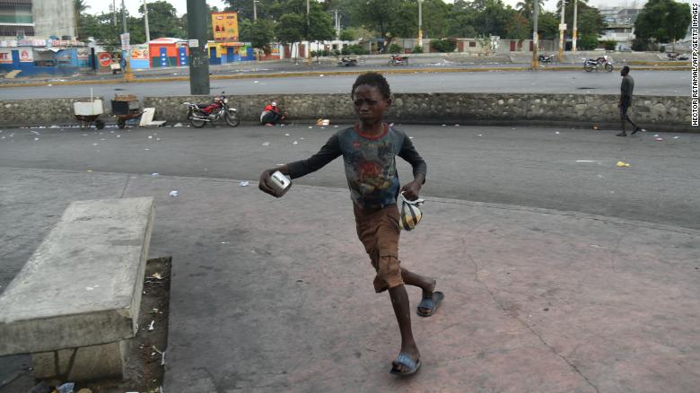 A boy flees from tear gas during clashes with Haitian police in Port-au-Prince on February 15, 2019.