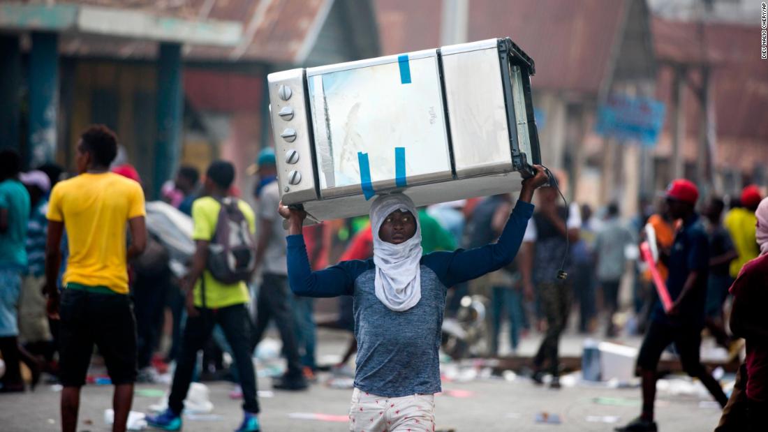A man carries a cooking stove during clashes in Port-au-Prince on Tuesday, February 12.
