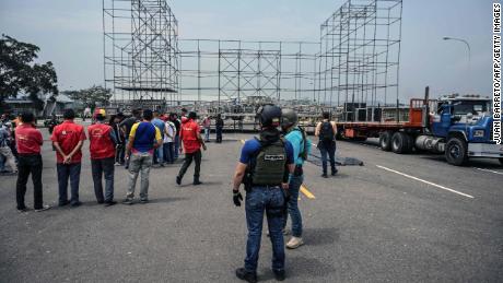 Workers prepare for a rival concert on the Venezuelan side of the bridge as a member of the country's intelligence service looks on.