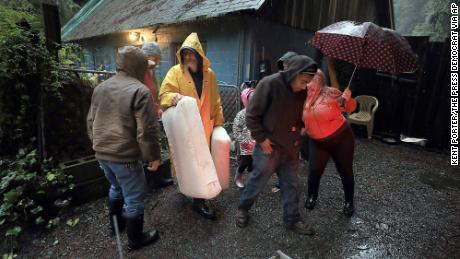 Tony Harley, middle, helps a friend evacuate Tuesday.