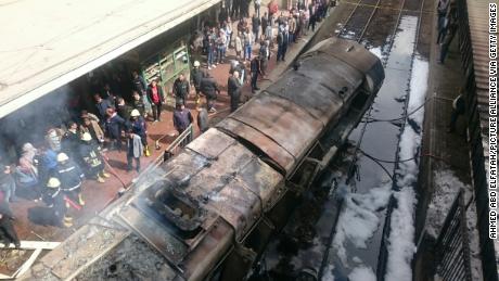 Rescue workers stand next to burned-out wagons sitting on railway tracks Wednesday in Cairo. 