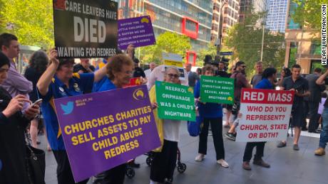 Protesters hold signs outside the County Court in Melbourne, Victoria on February 27, 2019 during a hearing for convicted pedophile Cardinal George Pell. 