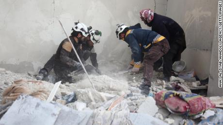 Members of the Syrian Civil Defense, a humanitarian group also known as the White Helmets, work at the site of the airstrike on Tuesday.