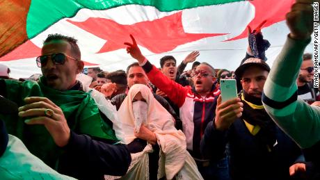 Algerians chant slogans under a national flag Friday in the capital.