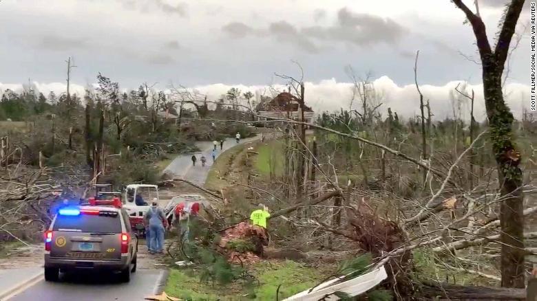 People clear fallen trees and debris on a road following a tornado in Beauregard, Alabama.