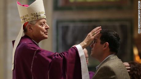 Cardinal Donald Wuerl places ashes on the foreheads of Catholics during Ash Wednesday Mass.